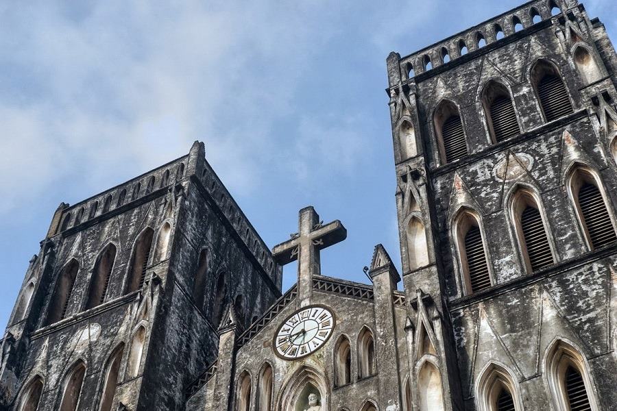 The stone cross on the top and the clock mounted on the facade