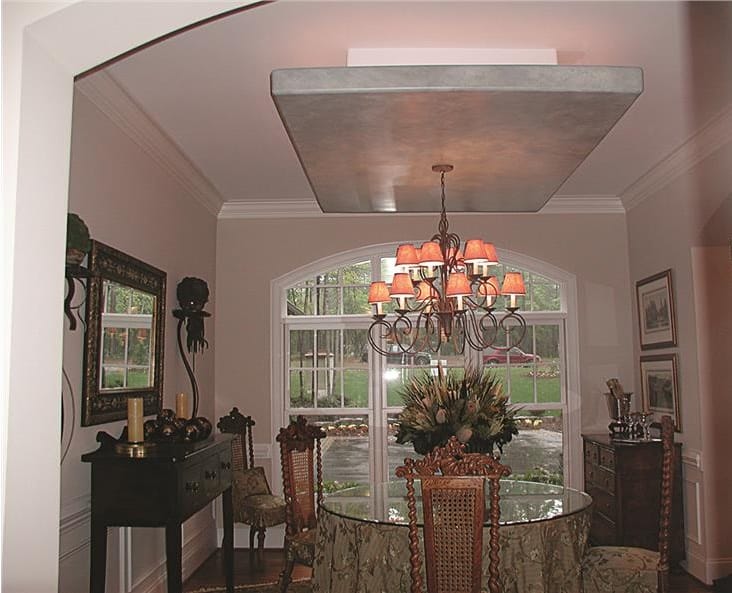 Formal dining room with dark wood buffet table and a round dining set illuminated by an ornate chandelier.