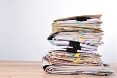 This  contain: a stack of papers sitting on top of a wooden table