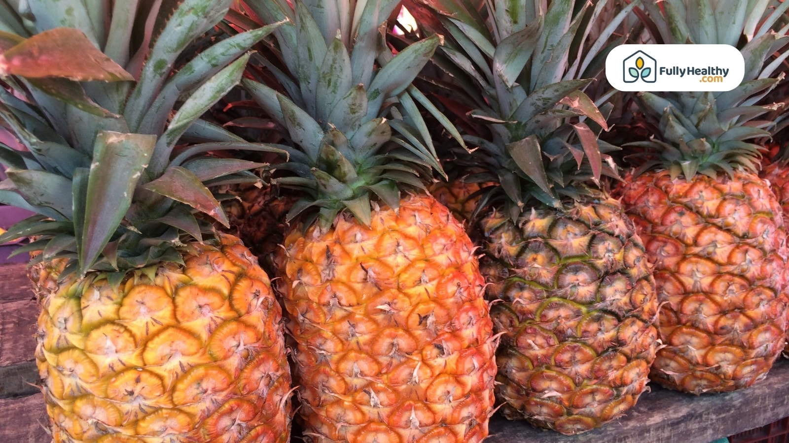 Ripe whole pineapples with green tops stacked at a fruit market