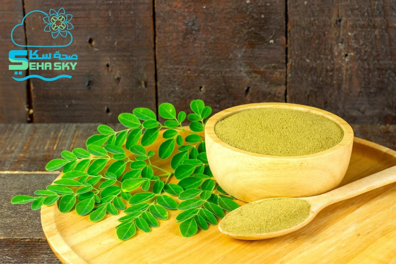 A bowl of powder and spoon with leaves on a wooden surface

Description automatically generated