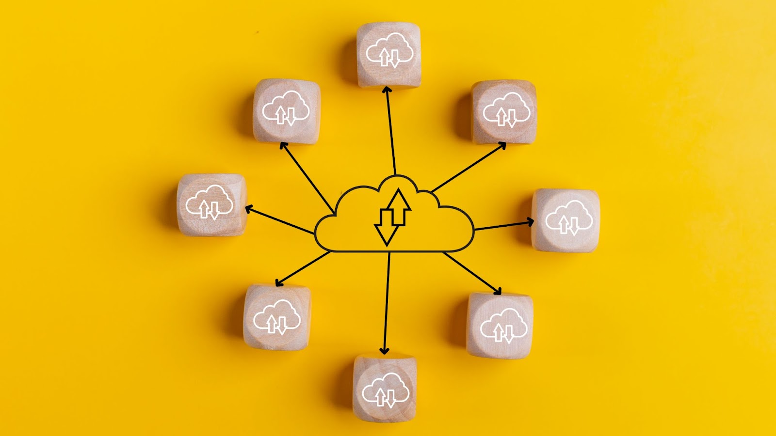 Eight wooden cubes with cloud icons connected by arrow lines are arranged around a central cloud drawing with up and down arrows, symbolizing cloud connectivity and data transfer.