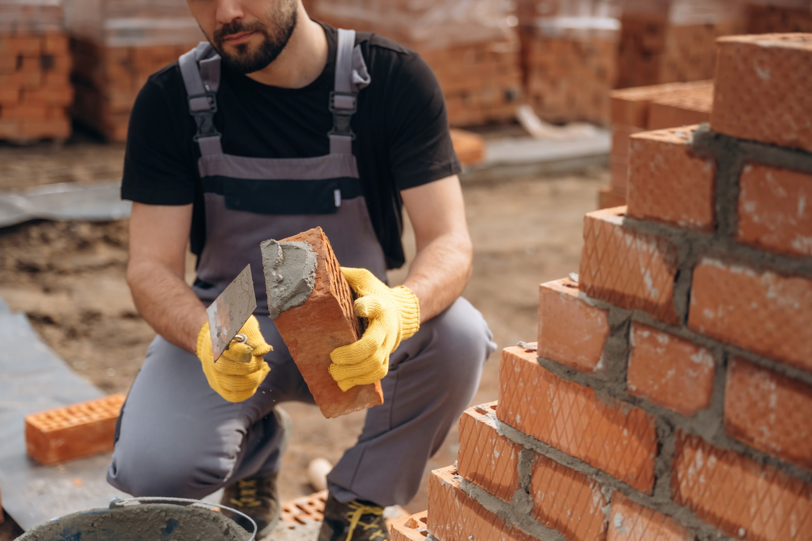 A man applying mortar to a brick