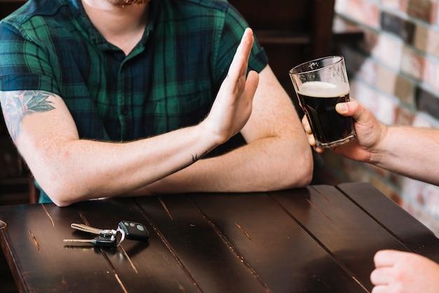 Man refusing glass of rum offered by his friend