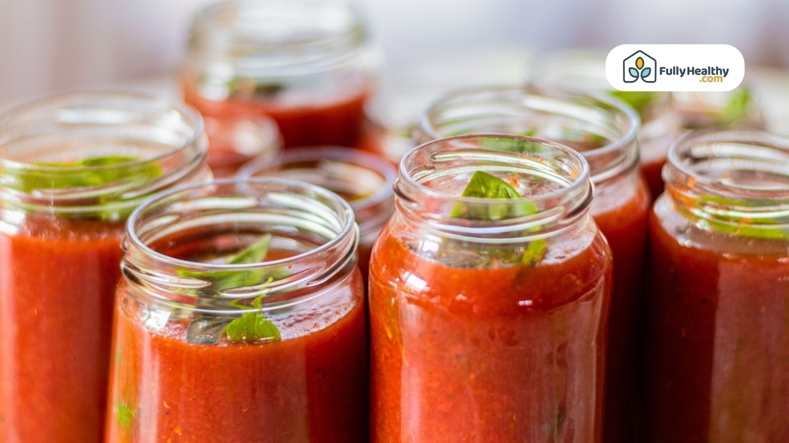 Glass jars filled with tomato sauce and fresh basil leaves