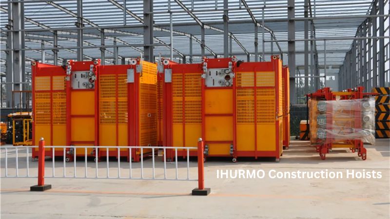 Red and yellow hoists are parked at a construction site with a steel-framed structure and small barrier visible.