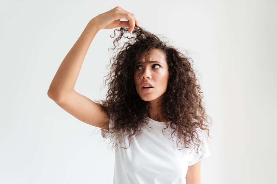 confused woman looking at her dry and brittle hair