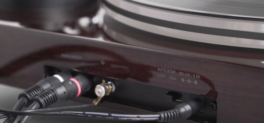 The back panel of a turntable showing connected RCA cables, ground wire, and power input.