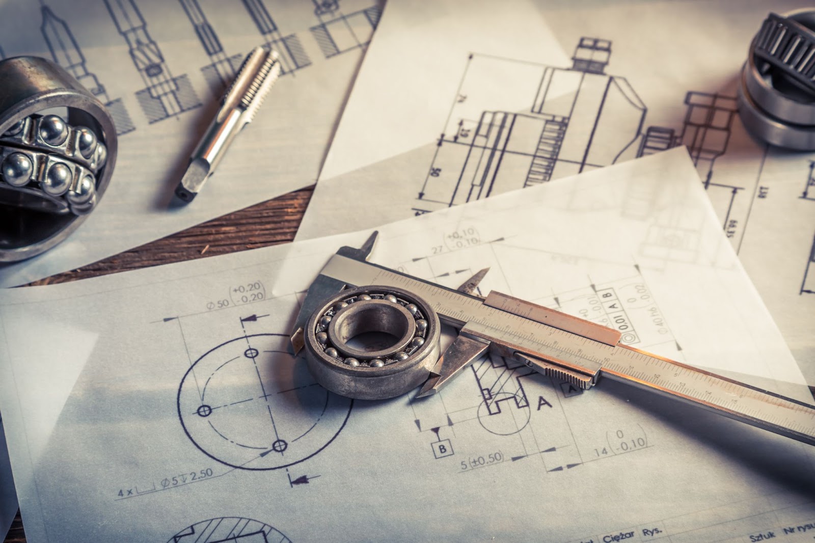 Mechanical parts and drawings on a desk, highlighting design challenges