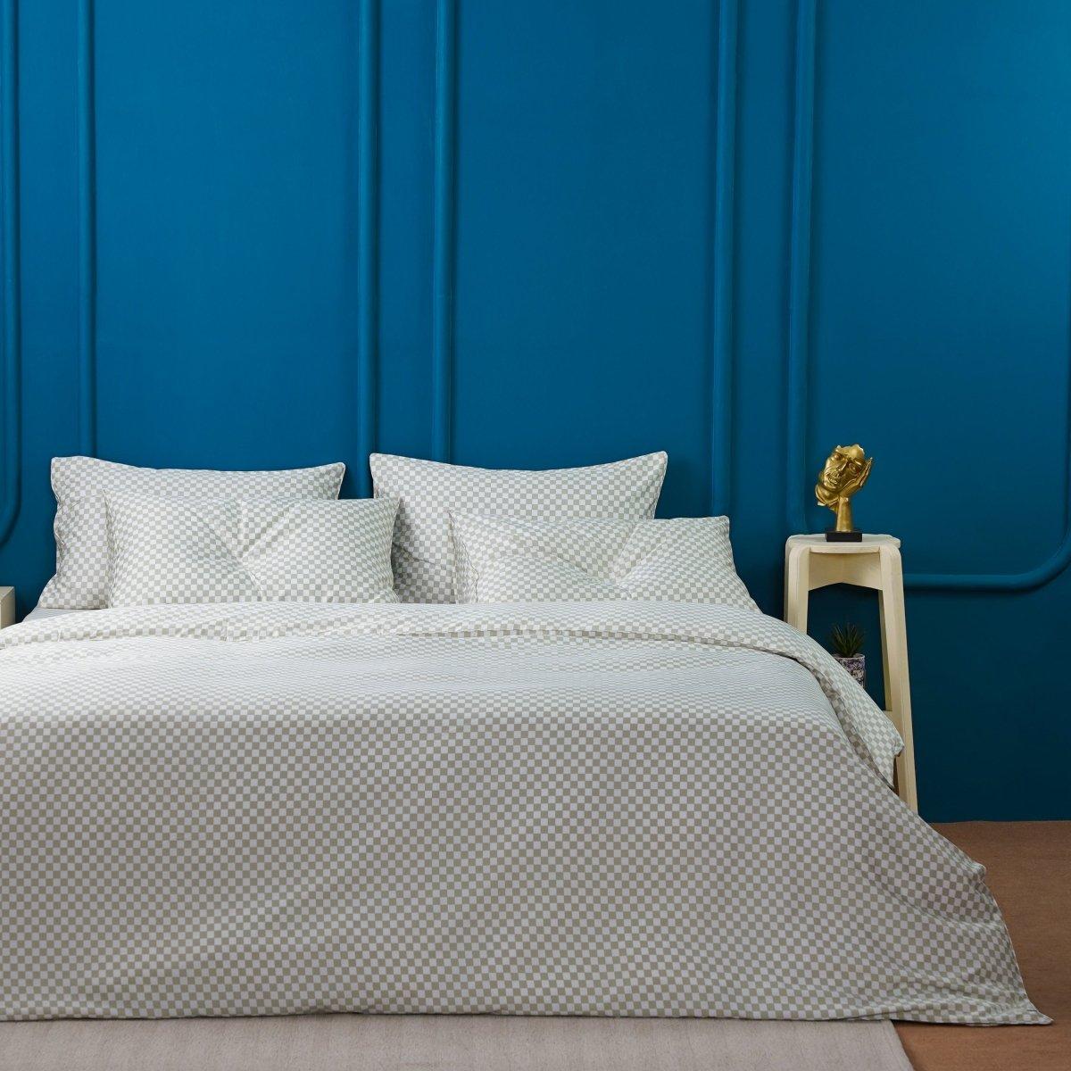 A bed with pillows and a table next to a blue wall