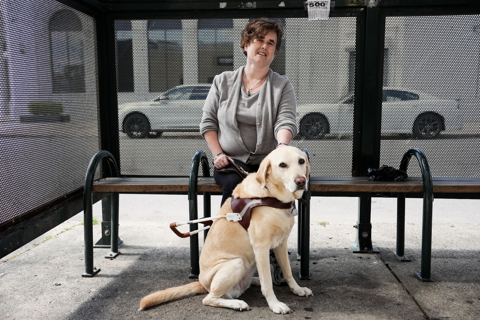 Dawn sits on a bench with her guide dog