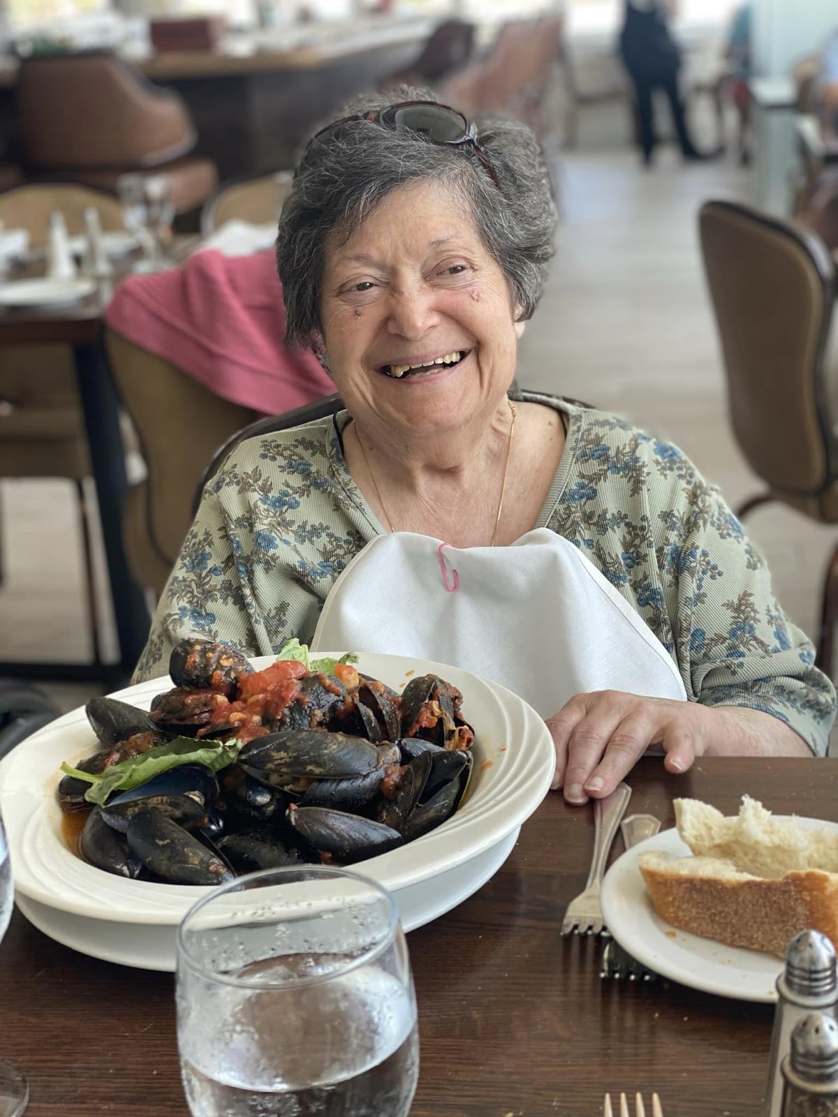 A senior smiling at a table with a plate of oysters in front of her