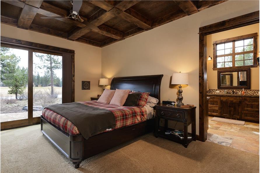 Primary bedroom with coffered ceiling, carpet flooring, and outdoor access via sliding glass doors.