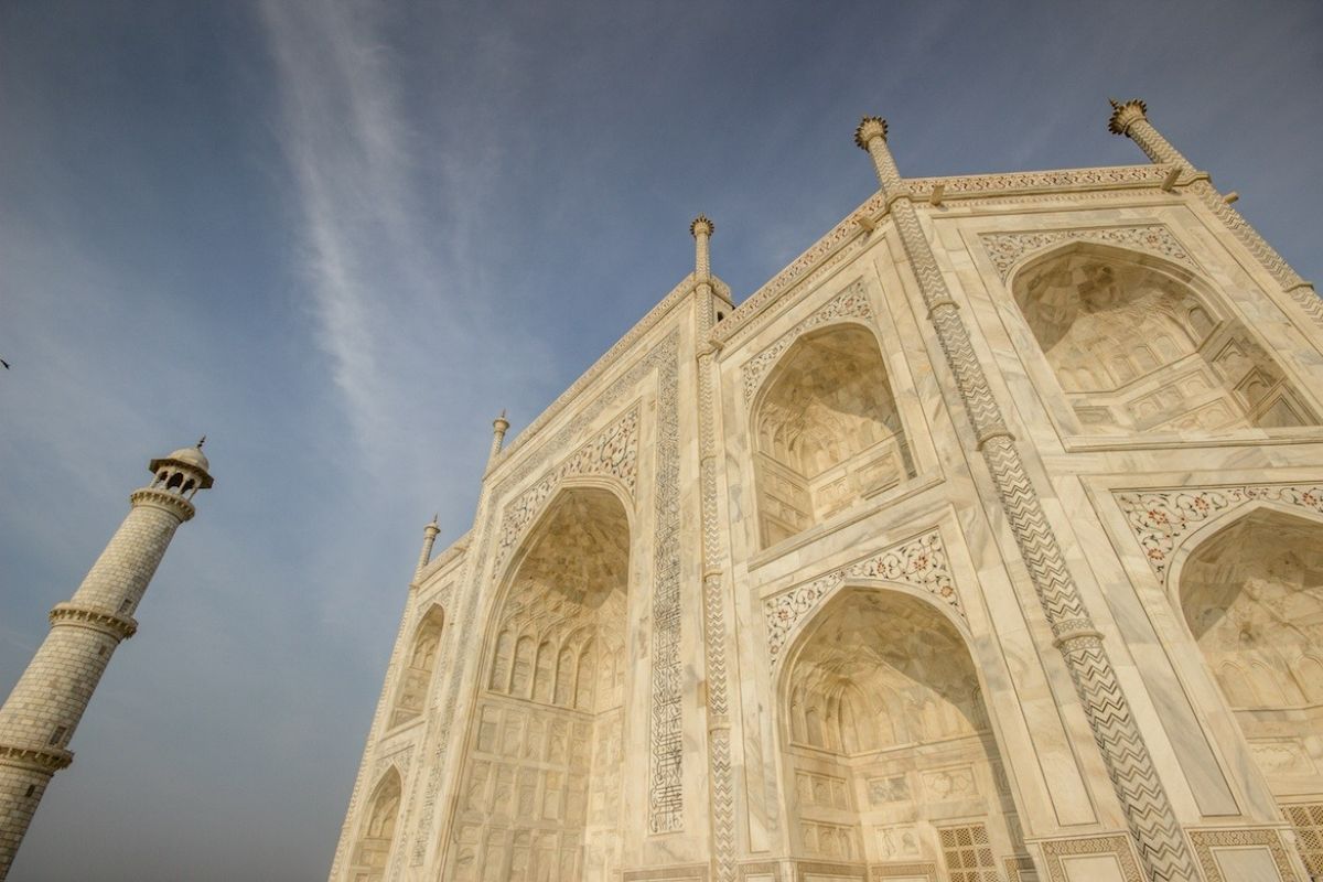  The image shows a close-up of an intricate geometric design inlaid with semi-precious stones on the white marble surface of the Taj Mahal.