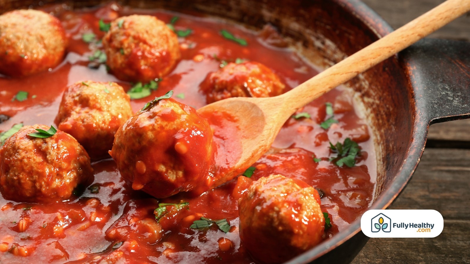 Juicy meatballs simmering in tomato sauce in a rustic iron skillet