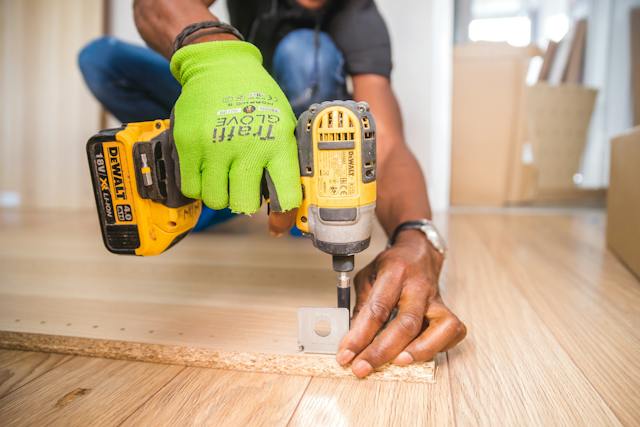 Someone drilling metal hardware into a piece of wood.