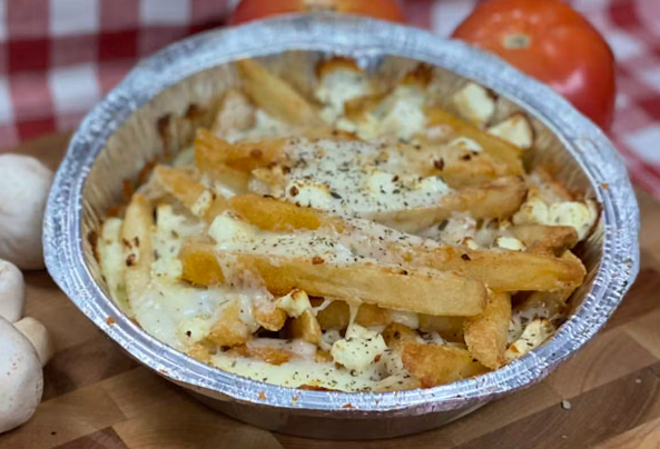 A cup of Greek fries topped with cheese by Manny and Olga's, placed on a wooden board