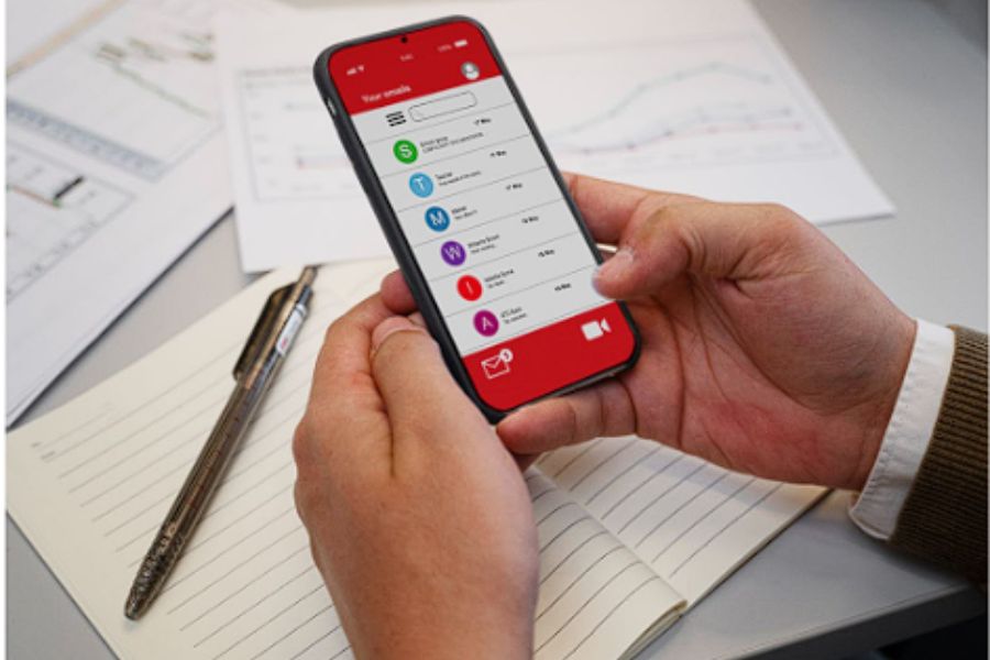 Person using a smartphone to manage contacts and messages at a desk.