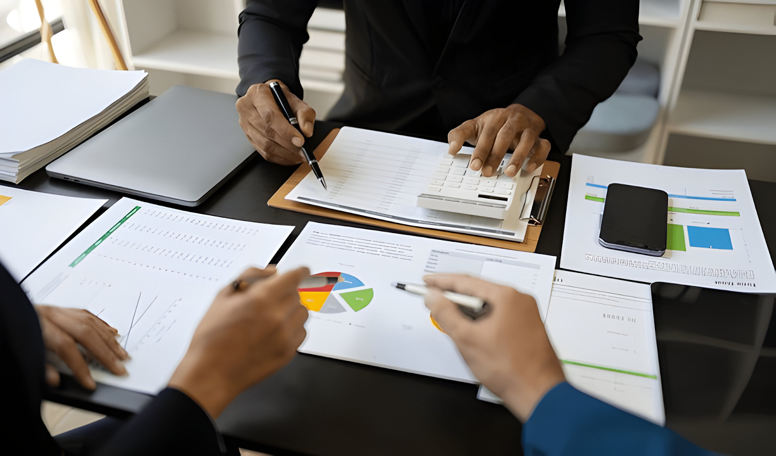 Accountants reviewing financial reports and using a calculator, representing the challenge of time-consuming manual processes in accounting tasks.