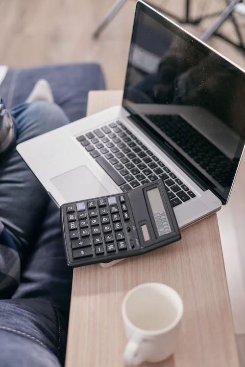 A laptop and calculator on a wooden desk