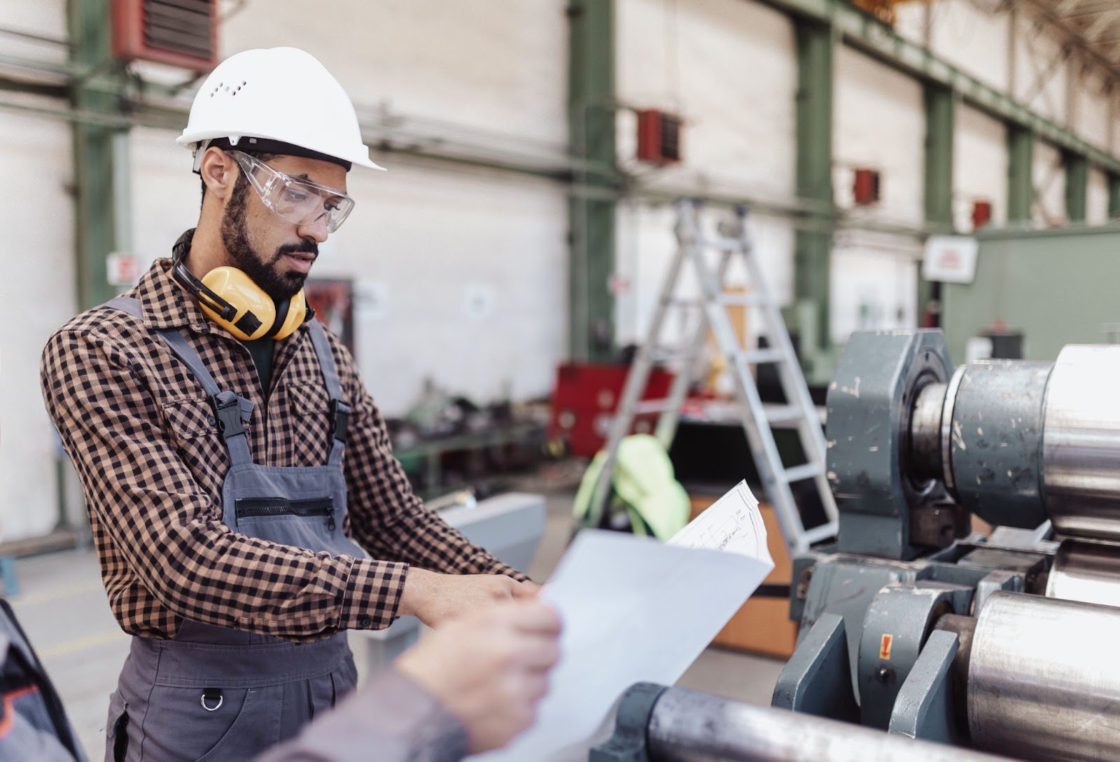 An engineer wearing safety equipment and discussing product design problems