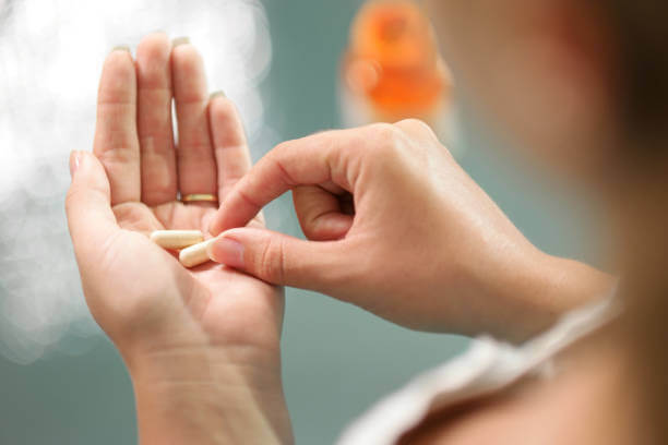 A person holding and taking a holy basil supplement, illustrating the ease and simplicity of incorporating it into a daily wellness routine.