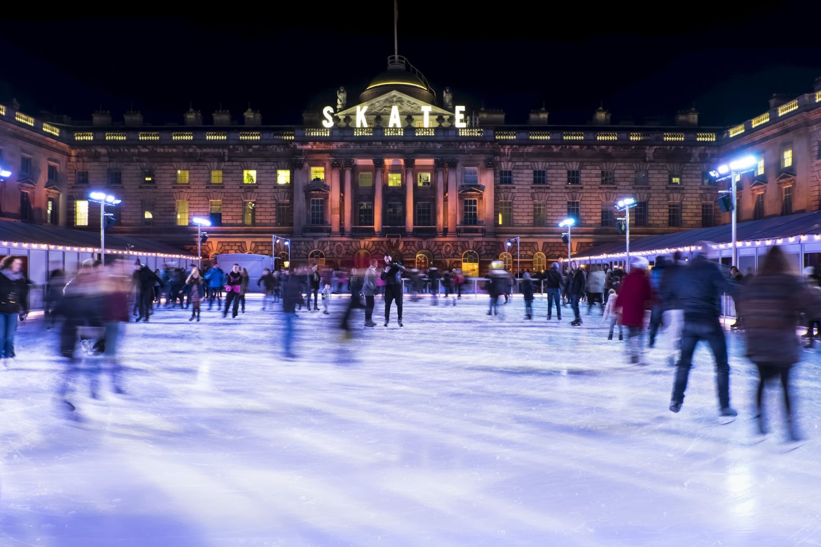 Families ice skating at Somerset House in London with festive lights and the historic building in the background