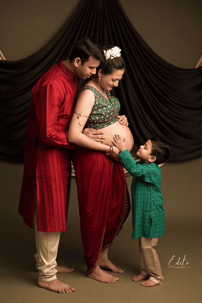 Traditional pregnancy photoshoot featuring a family sharing a tender moment around the baby bump