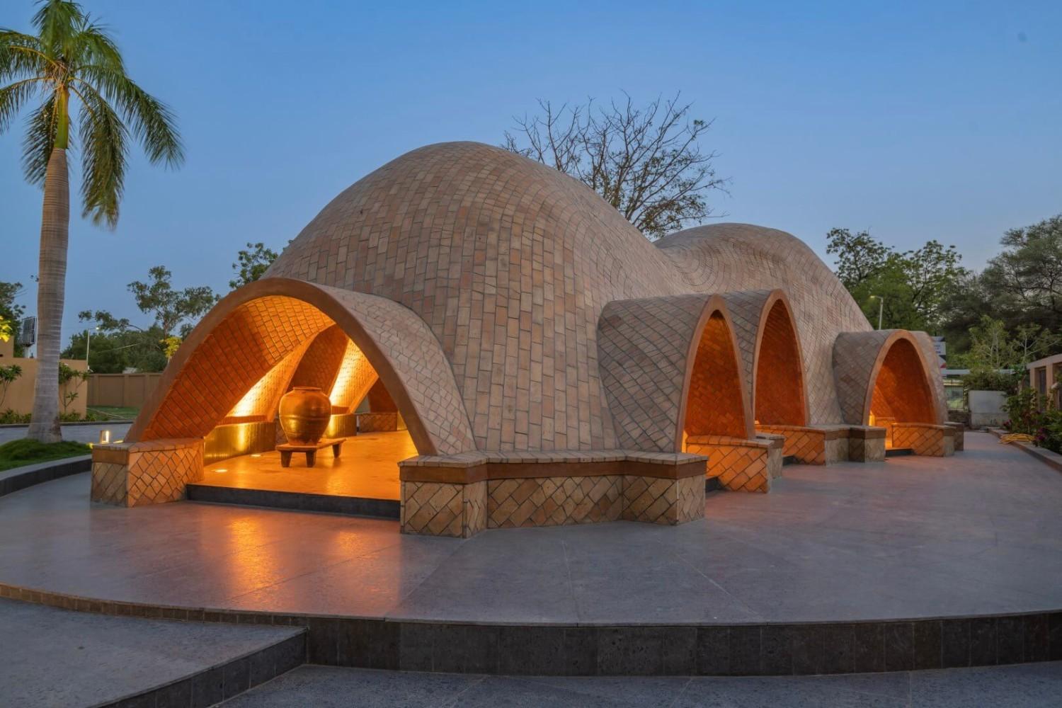 An architectural photography featuring a series of brick, dome-shaped arches illuminated from within during twilight, showcasing intricate architectural details.