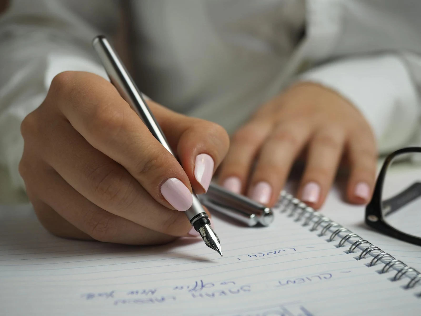 https://www.pexels.com/photo/woman-in-white-long-sleeved-shirt-holding-a-pen-writing-on-a-paper-110473/