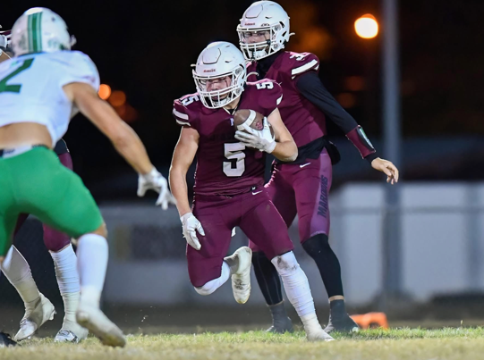 A football player running with a football

Description automatically generated