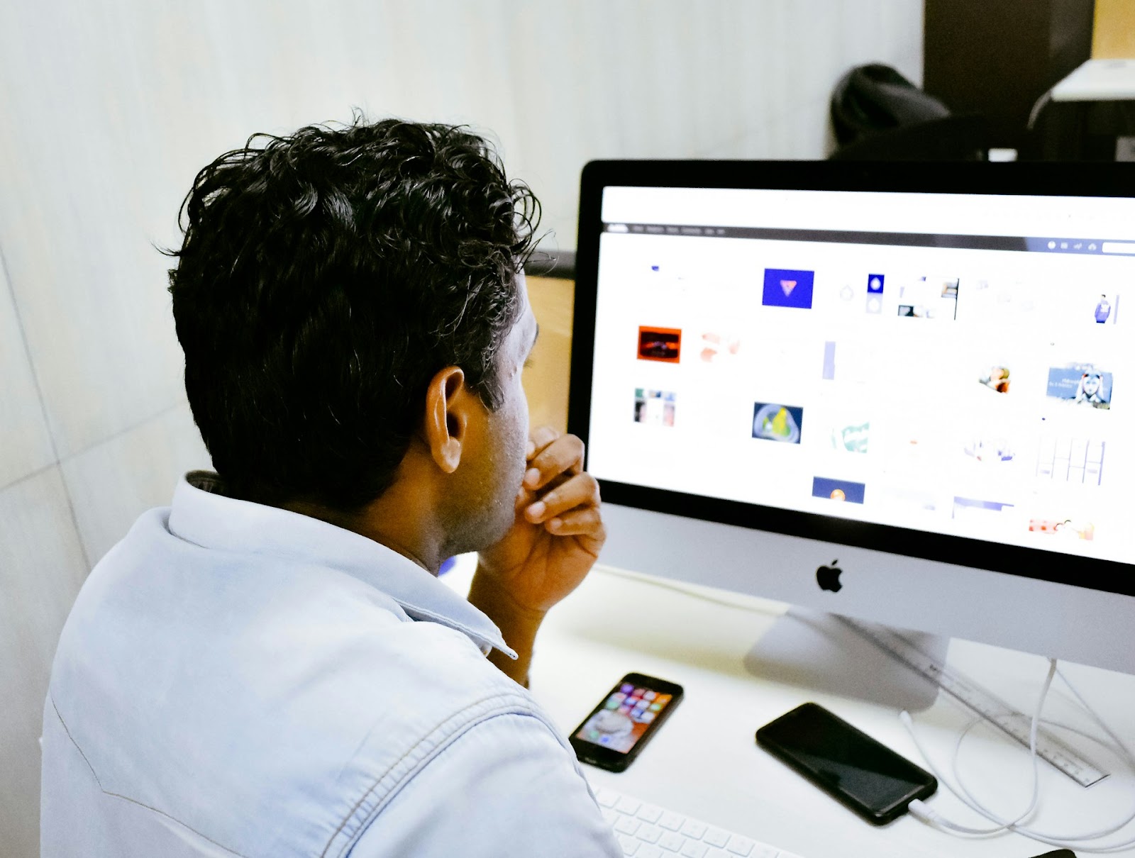 A man at a desk, intently looking at a computer screen while working on his tasks.