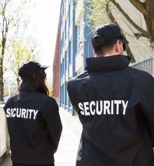 This contains an image of two security officers walking down the street