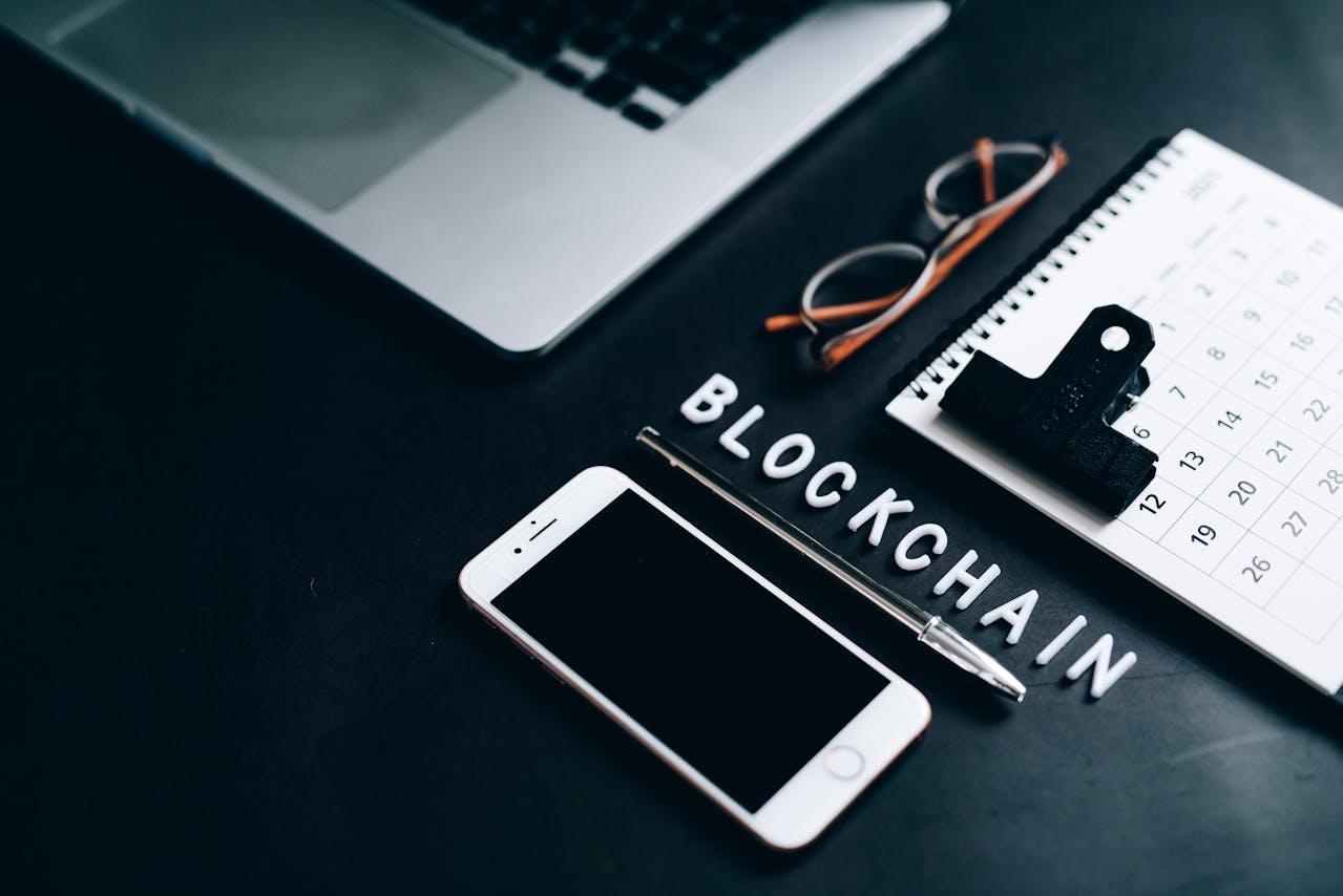 Desk photo with a phone and calendar with the word "Blockchain"