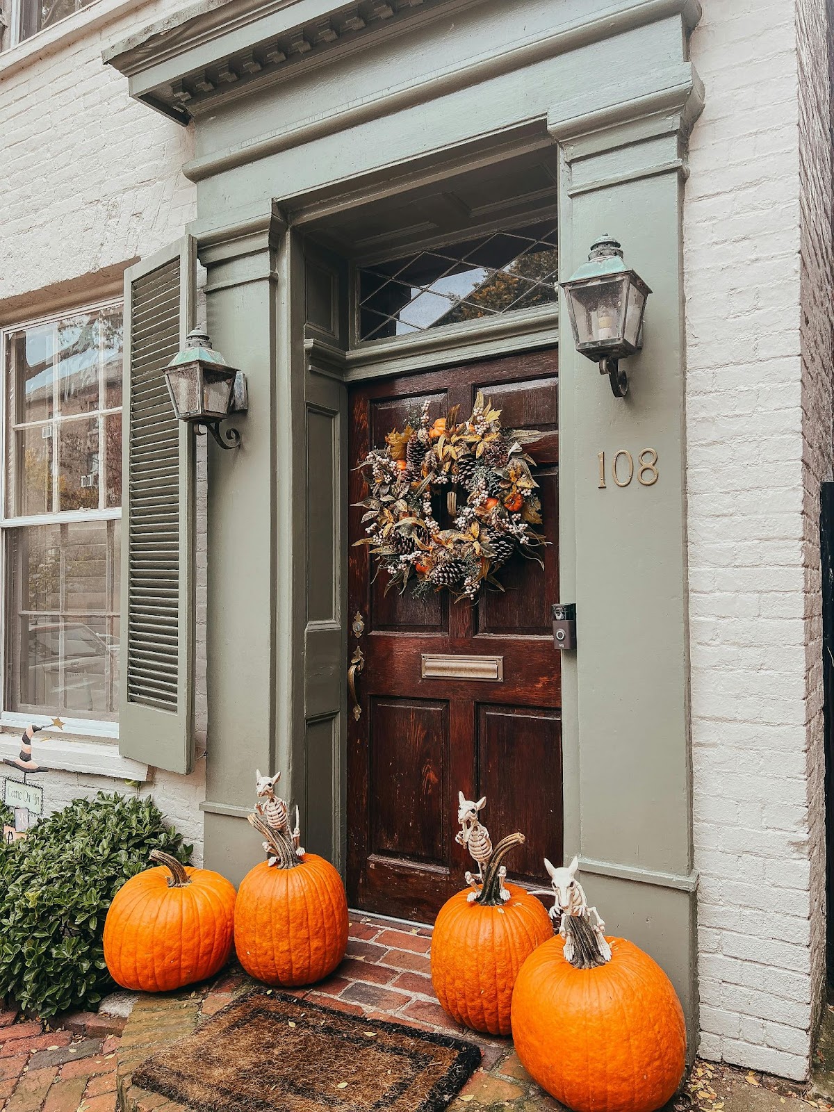 A front door with a fall-themed wreath and pumpkins