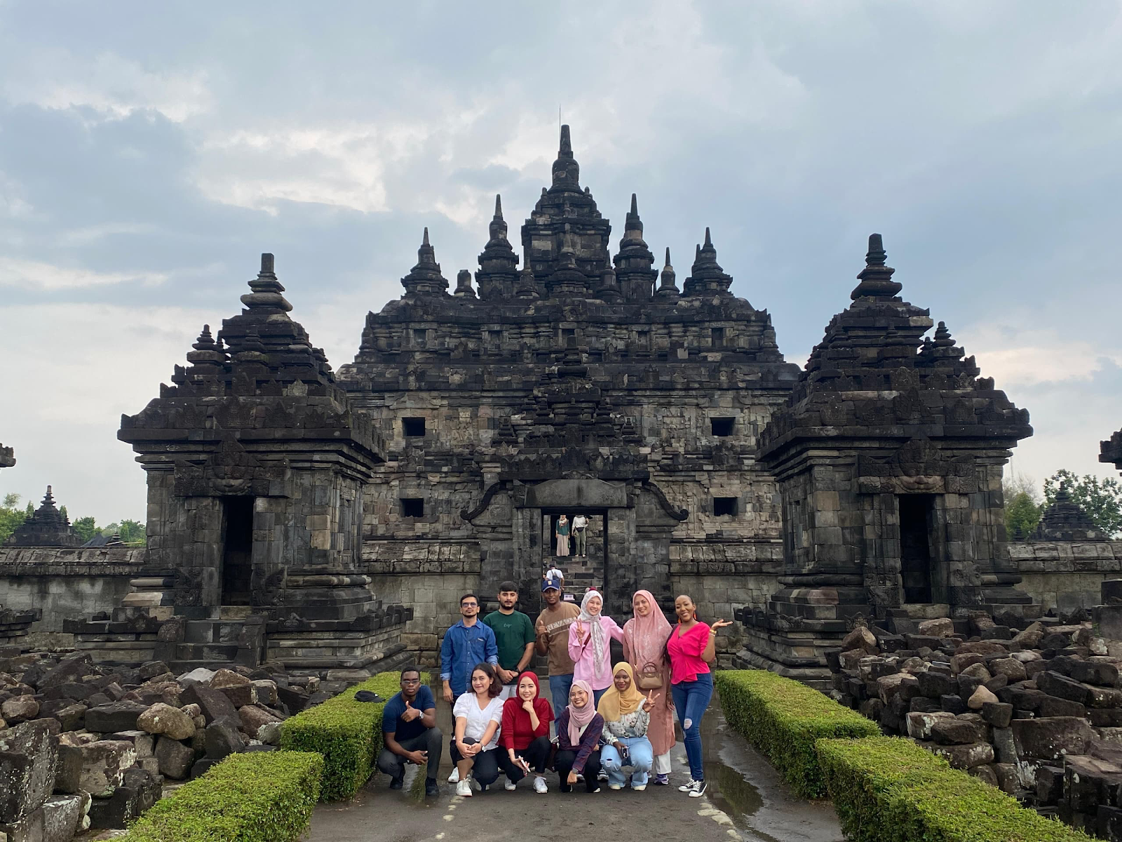 A group of people posing for a photo in front of a stone building

Description automatically generated