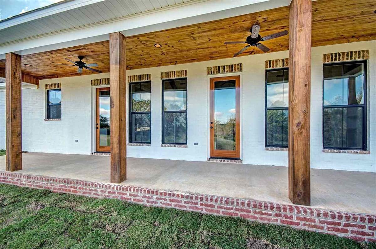 Rear covered porch with two glass doors, aluminum framed windows, and wooden columns.