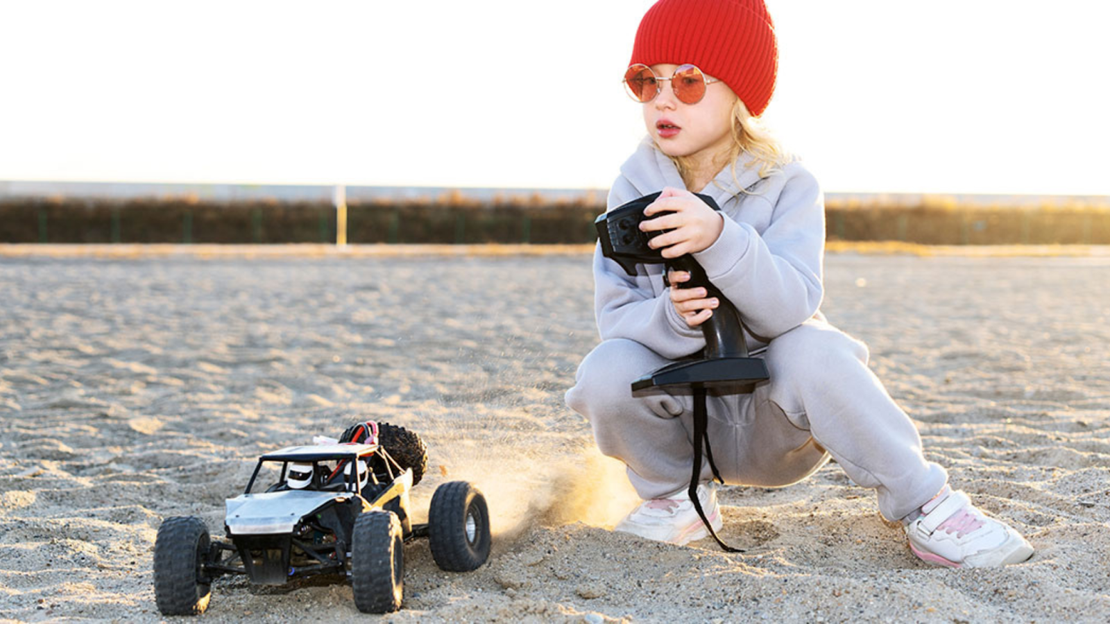 A Baby girl playing with a remote control toy car on the beach | Royal Ramakra