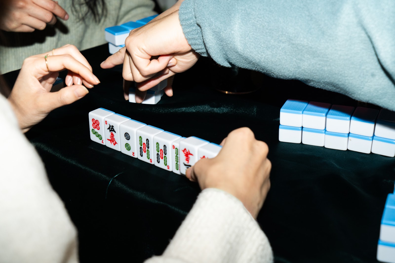 Alt text: Close-up of hands playing mahjong.