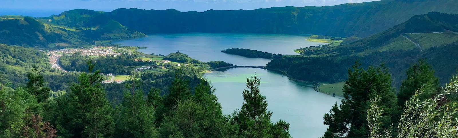 Panorama da Lagoa das Sete Cidades cercada por montanhas verdes, representando um dos principais atrativos de onde fica a Ilha de São Miguel, em Portugal.
