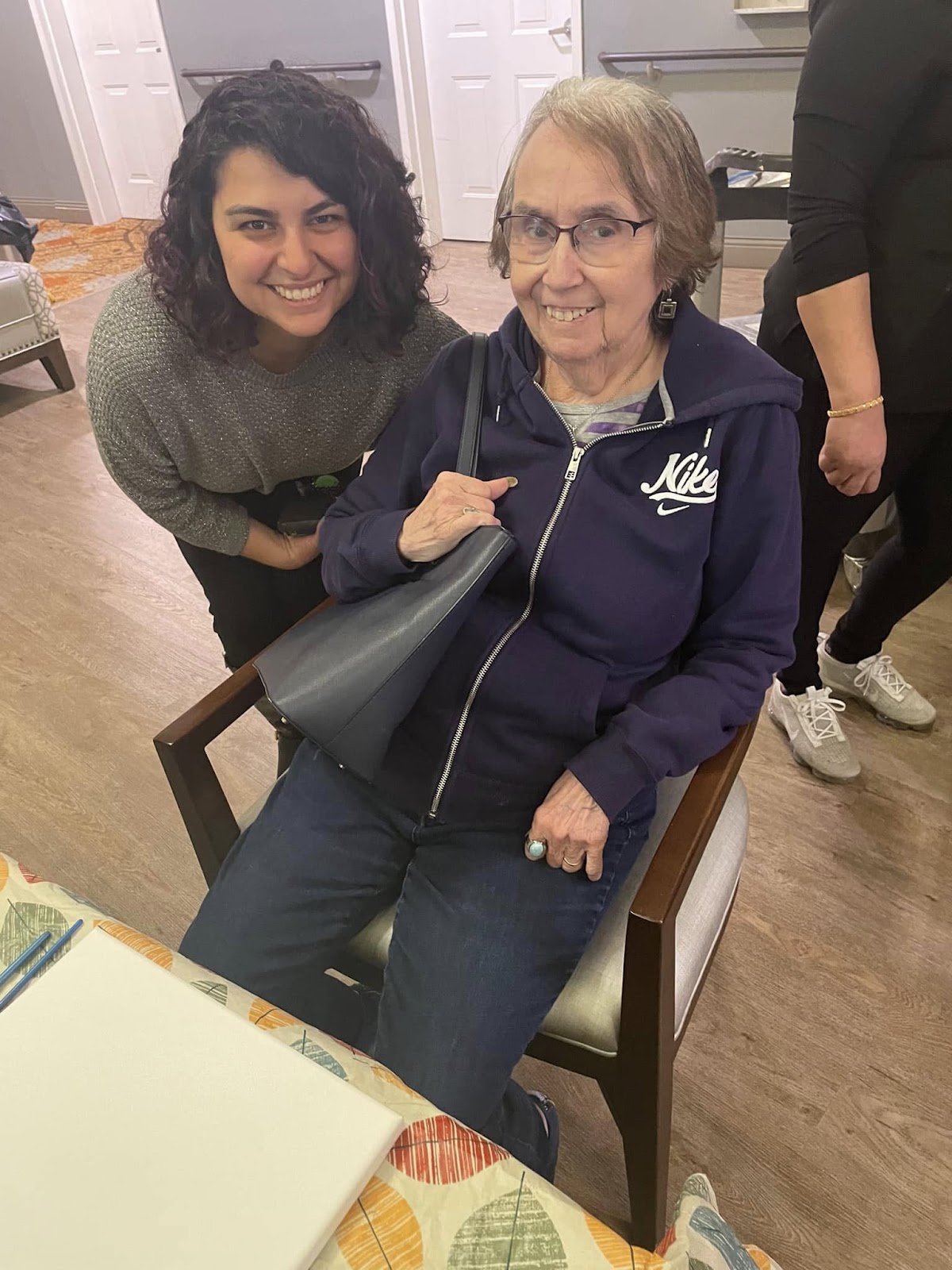 A picture of a caregiver and senior adult smiling at a table in a kitchen