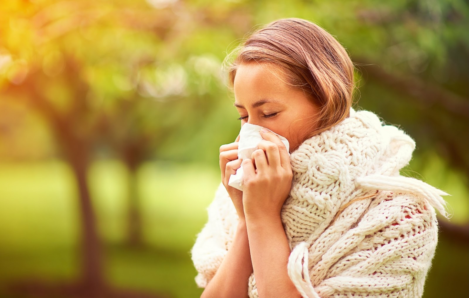 A woman sneezing from allergies. 