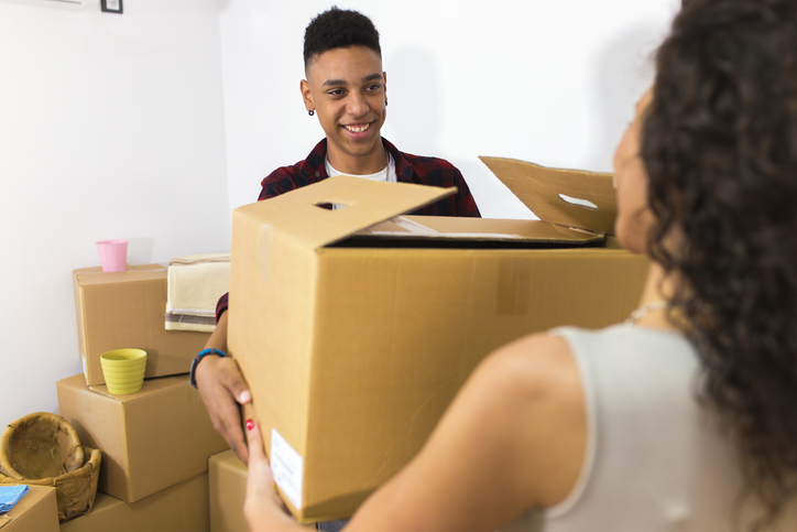 A man and woman carrying packed boxes as they prepare to move.