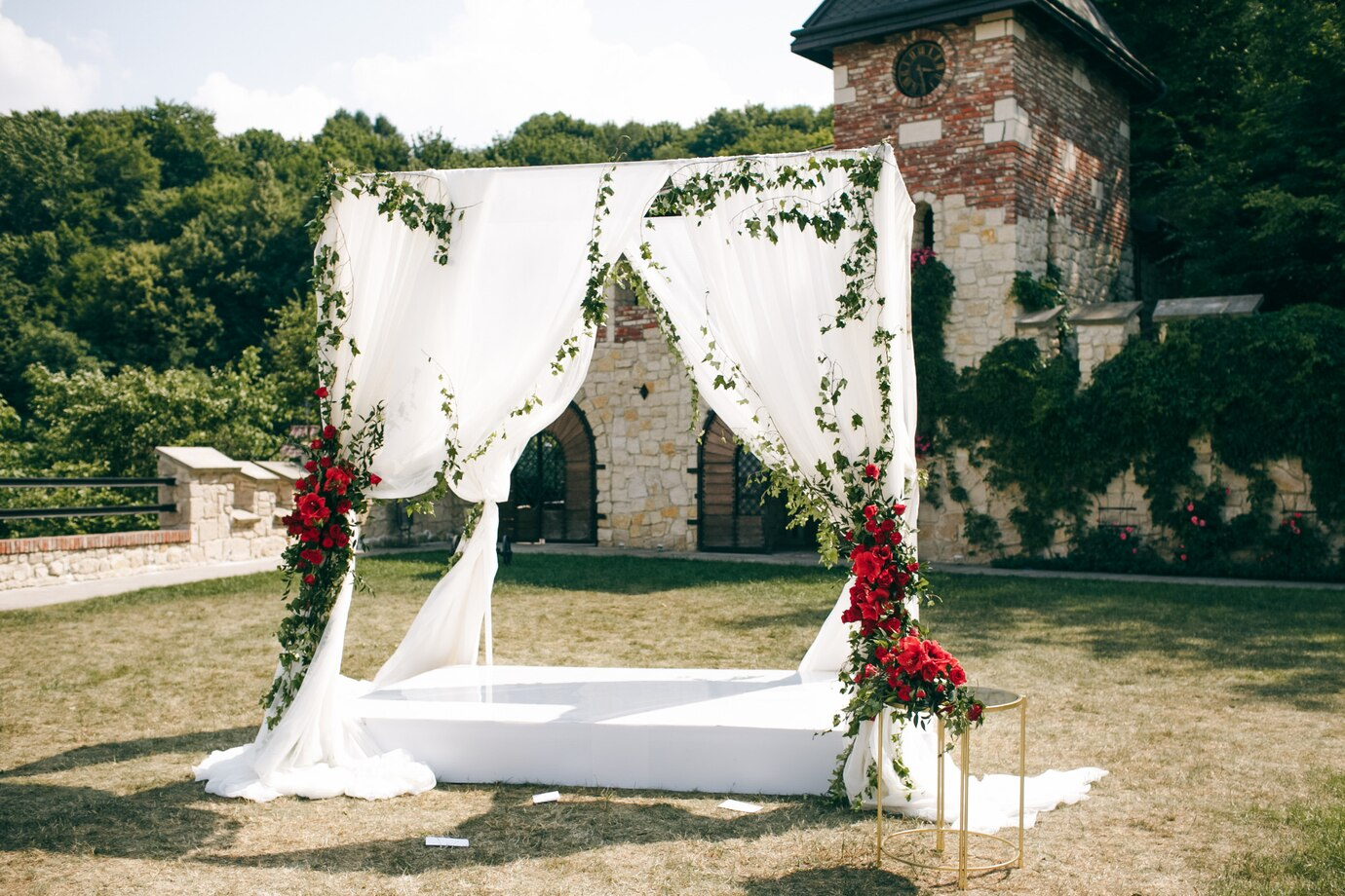 Romantic gazebo decorated with fresh flowers and draped fabric, perfect for an outdoor wedding ceremony under the open sky.

