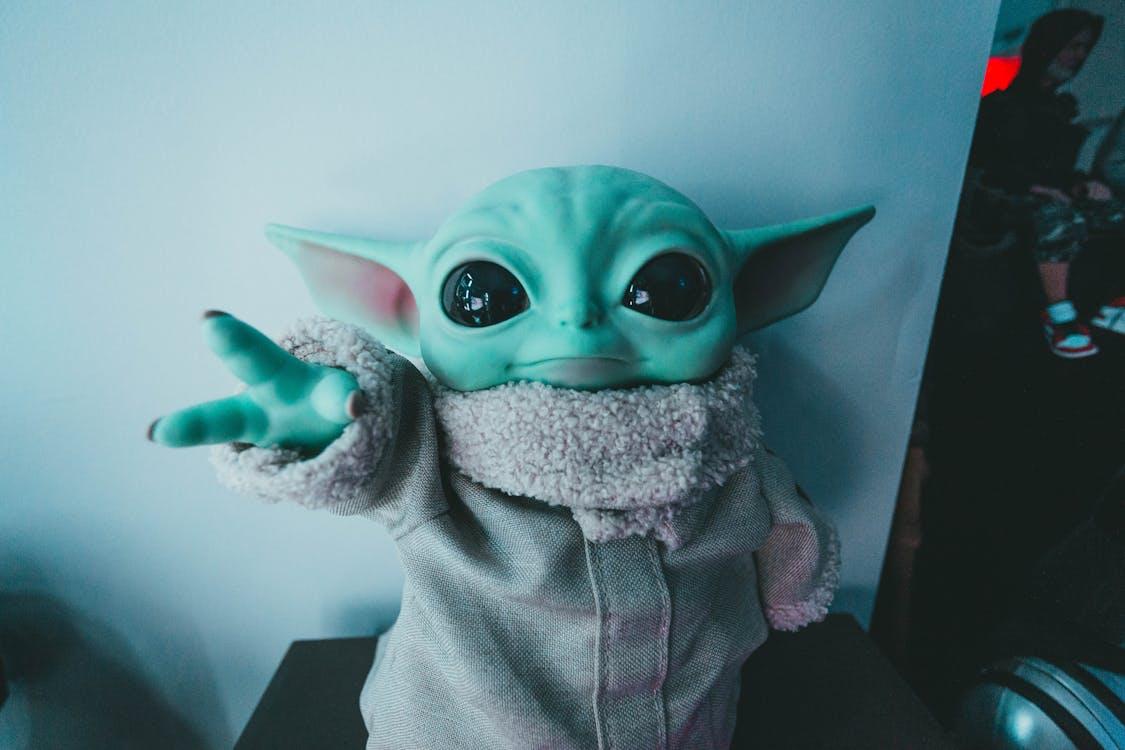 Cute Baby Yoda toy figurine in a cozy outfit reaching forward, perfect for fans.