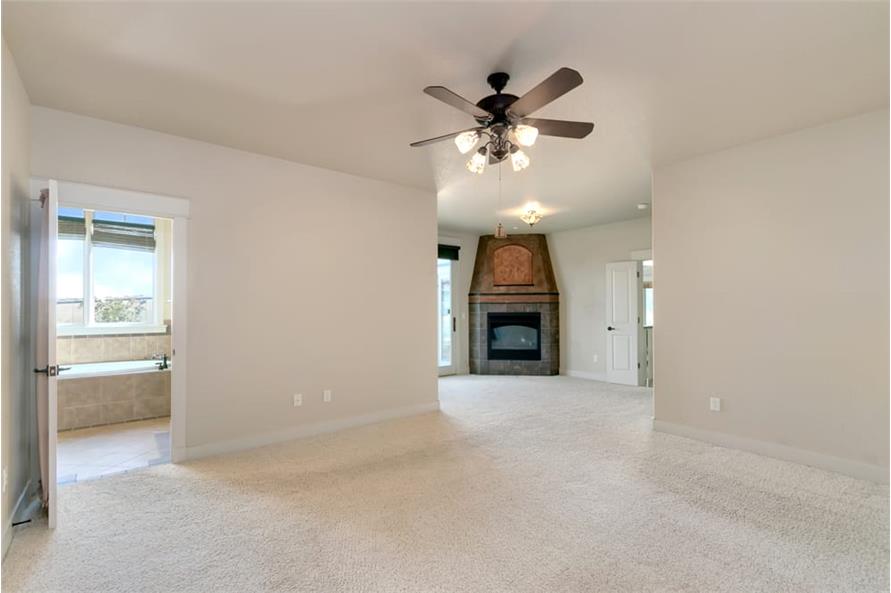 Spacious primary bedroom with carpet flooring, a corner fireplace, and private ensuite.