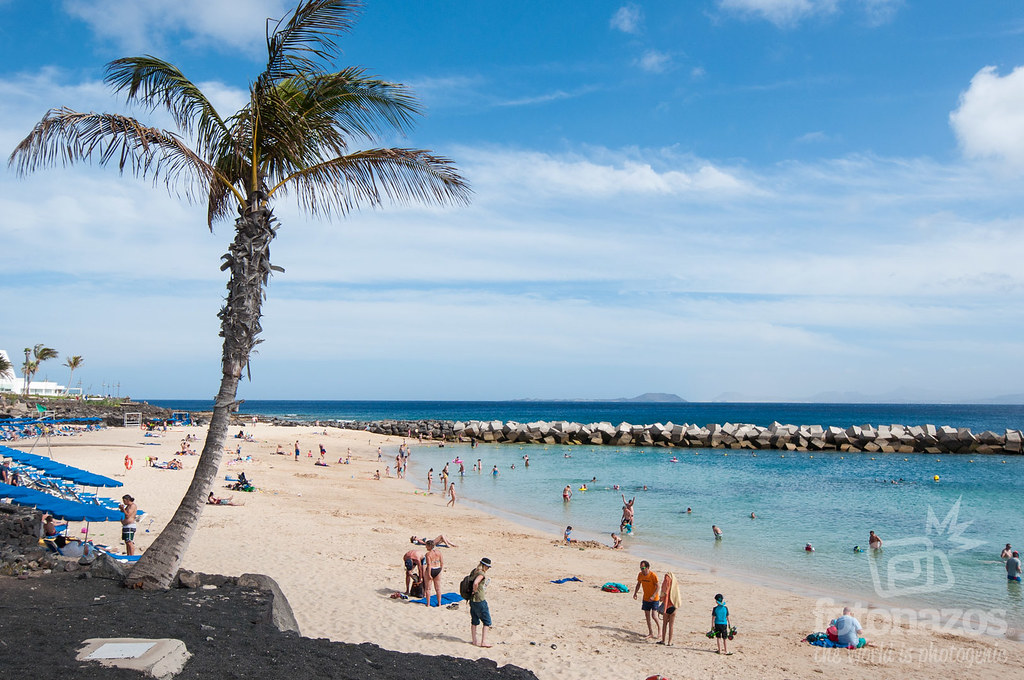 There were so many people enjoying on the sandy beach with clear water and solid rocks border there