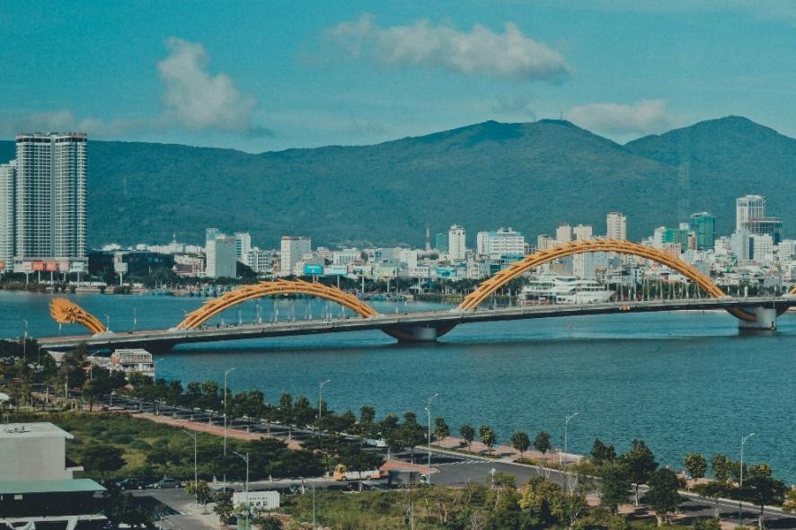 A bridge over water with a city in the background

AI-generated content may be incorrect.