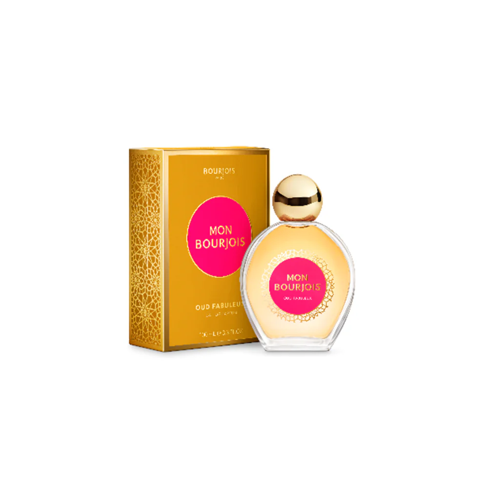 A round perfume bottle of Bourjois Mon Bourjois Oud Fabuleux with a gold cap, placed next to its golden packaging with pink detailing.