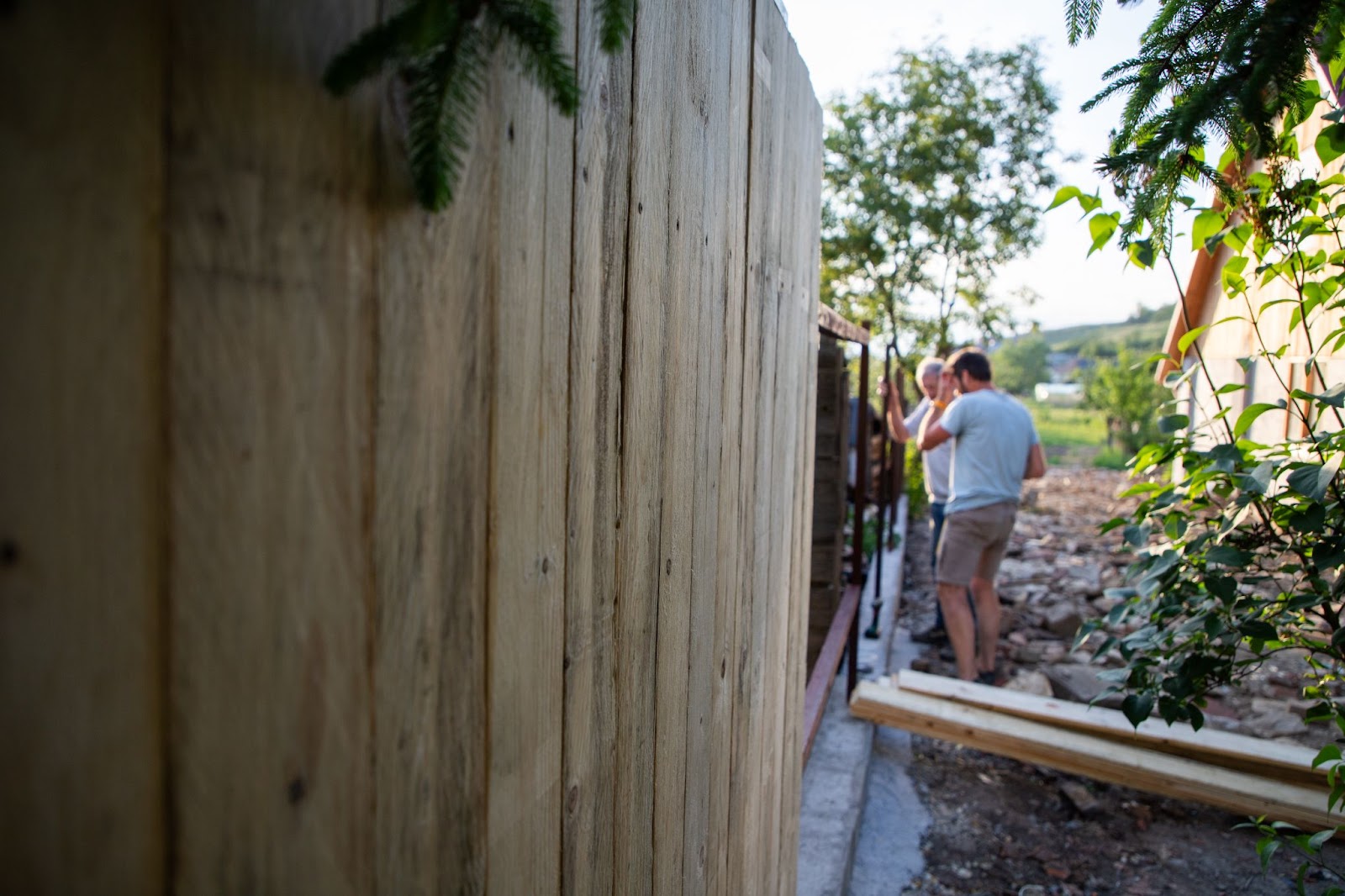 Father and son assess the area for installing a wooden fence, planning layout and measurements.